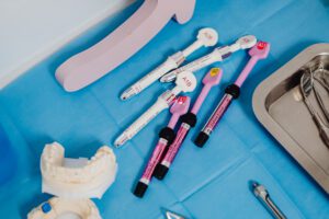 Prophylaxe A detailed view of dental instruments and materials arranged on a sterile blue surface in a clinical setting.