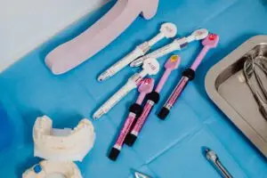 A detailed view of dental instruments and materials arranged on a sterile blue surface in a clinical setting.